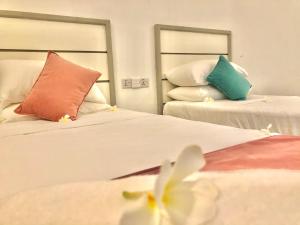 een hotelkamer met 2 bedden en kleurrijke kussens bij Moon Isle Beach Bungalow in Nilaveli