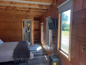 een slaapkamer met een bed, een tv en een raam bij HelChiloé Cabañas in Piruquina