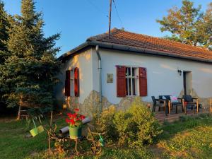 Cette petite maison blanche dispose de fenêtres rouges et d'une terrasse. dans l'établissement Tiszai Fenyves Apartman, à Tiszadorogma