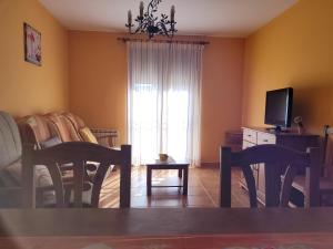 a living room with a table and chairs and a television at Apartamentos El Prado FAMILIAS in Valbona +25 photos