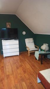 a living room with a tv and a chair and a table at Dom na Górce in Gorlice