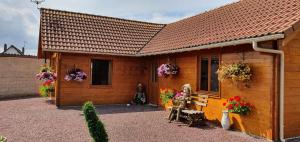 a wooden cabin with flowers on the side of it at Le chalet in Saint-Quentin-Lamotte-Croix-au-Bailly