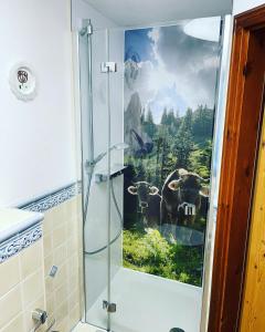ein Badezimmer mit einer Dusche und einem Kuhgemälde in der Unterkunft Landgasthof Zum Alten Reichenbach in Nesselwang