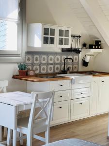 uma cozinha com armários brancos, um lavatório e uma mesa em Loft Naturalpina Dolomiti Farm em Belluno