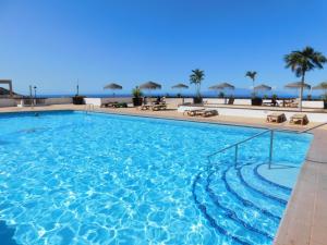 een groot zwembad met de oceaan op de achtergrond bij Costa Adeje Sunset Apartment in Adeje