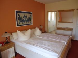 a bedroom with a large white bed with orange walls at Hotel Wilhelmshof in Ribnitz-Damgarten