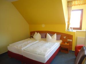 a bedroom with a bed with yellow walls and a window at Hotel Wilhelmshof in Ribnitz-Damgarten