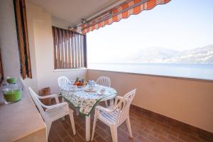 a table and chairs in a balcony with a view of the water at Peler Beth's House in Brenzone sul Garda