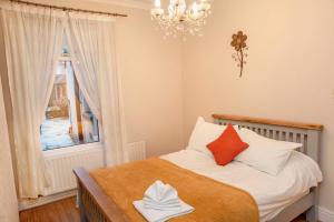 Dormitorio pequeño con cama con almohadas de color naranja y blanco en Lennard House en Newport