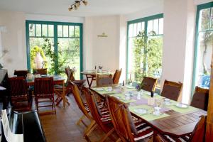 ein Esszimmer mit Tischen, Stühlen und Fenstern in der Unterkunft Pension Landhaus Teichgraf in Wolgast