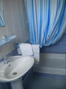 a bathroom with a sink and a toilet and a blue shower curtain at L 'Acropole in Nissan-lez-Enserune