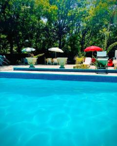 uma piscina com guarda-sóis, mesas e cadeiras em La Casita Inn Bustamante em Bustamante