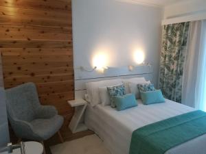 a bedroom with a white bed and a chair at Alo Baía São Lourenço in Santa Bárbara