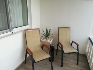 two chairs sitting on a porch next to a window at Alo Baía São Lourenço in Santa Bárbara