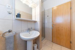 een badkamer met een wastafel en een houten deur bij Apartments Leonarda in Murter +34 foto's
