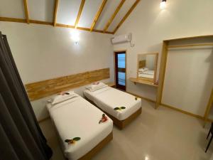 two beds in a room with a mirror and a window at Thoddoo Haisha inn, Maldives in Thoddoo