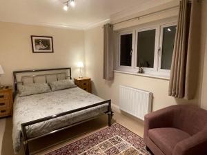 a bedroom with a bed and a chair and a window at Graceland Farm B&B in Brockenhurst