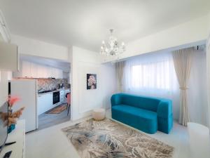 a living room with a blue couch and a kitchen at Unique Hotel Apartments Iasi in Iaşi