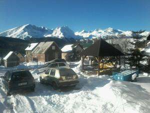 two cars parked in the snow with mountains in the background at Guesthouse Mijatovic in Žabljak