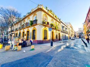 a yellow building on a city street with people sitting outside at ATICO DUPLEX ALAMEDA de HERCULES GRAN TERRAZA in Seville