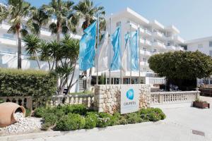 um hotel com bandeiras azuis e brancas em frente em Grupotel Los Príncipes & Spa em Playa de Muro
