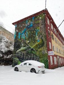 a white car parked in the snow in front of a building at Neverending Nature León in Tremor de Arriba