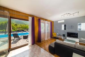 a living room with a couch and a large window at Holiday Home Villa Marija in Radošić