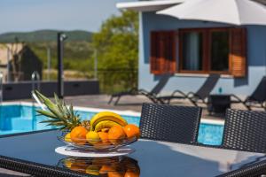 uma taça de fruta numa mesa ao lado de uma piscina em Holiday Home Villa Marija em Radošić