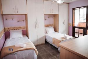 a small room with two beds and a desk at Casarão do Bosque a 200 m da praia | ROUR218 in Rio das Ostras