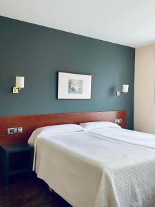 a bedroom with two beds and a blue wall at Hotel Yerri in Estella