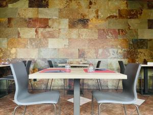 a table with chairs in front of a brick wall at Hotel Yerri in Estella
