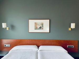 a hotel room with a bed, lamp, and paintings on the wall at Hotel Yerri in Estella