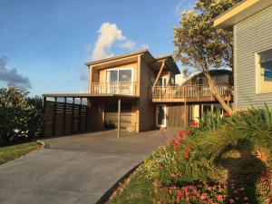 a house with a deck on a driveway at Chalet Cullen, in Mangawhai