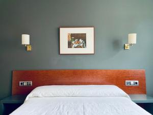 a bedroom with a bed and two lights on the wall at Hotel Yerri in Estella