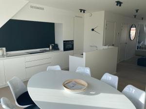 a white kitchen with a white table and white chairs at Ghibli - Duplex with parking in Knokke-Heist