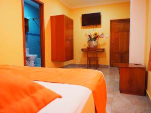 a bedroom with a bed and a bathroom with a tv at Hostal España in Puerto Ayora