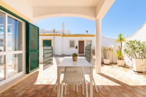 una mesa blanca y sillas en un patio con una casa en Cozy and sunny villa just some steps from the sea, en Luz