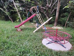 a playground with a red slide and a swing at Terras de Bragança in Bragança Paulista