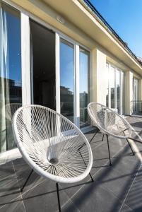 Duas cadeiras brancas sentadas numa varanda com janelas em Penthouse Apartments, The Luxury Suites em Tessalônica