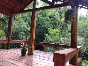 a wooden deck with a bench and a potted plant at Pousada Chalés da Lua in Munhoz