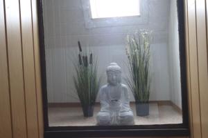 eine Statue, die neben einigen Pflanzen in einem Raum sitzt in der Unterkunft SEA YOU- Ruhige Wohnung mit Terrasse nur 5 Minuten zur Müritz in Marienfelde