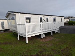 3 Bedroom Modern Caravan Sleeps up to 8 في ميلوم: منزل متنقل أبيض مع شرفة وسطح