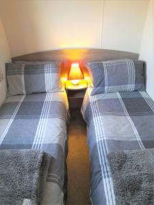 two beds in a room with a lamp between them at 3 Bedroom Modern Caravan Sleeps up to 8 in Millom