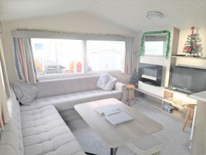 3 Bedroom Modern Caravan Sleeps up to 8 في ميلوم: غرفة معيشة مع أريكة بيضاء وطاولة