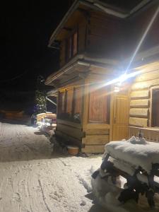 a snow covered cabin with the light shining on it at Góralskie Pokoje in Witów