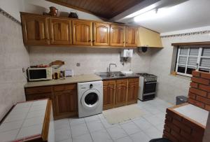 cocina con armarios de madera y lavadora en Góis - Belas Vistas na N2 - AL en Góis