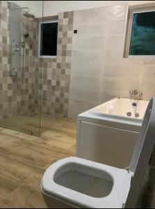 a bathroom with a toilet and a sink and a shower at AlanVal Suites in Accra