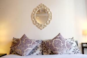 a mirror on a wall above a bed with pillows at La Torre del Moro - RH Collection in Rome