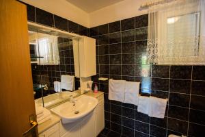 a black tiled bathroom with a sink and a mirror at House Maca in Palit +63 photos