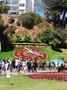 La gente caminando alrededor de un reloj de flores en un parque en Bello Departamento Viña, en Viña del Mar